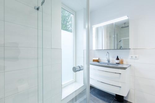 a white bathroom with a sink and a shower at Mozart's Garden Villa in Salzburg