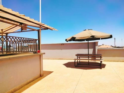 an umbrella and a bench on a balcony at Pine Residency w Secure Parking, Wifi, Netflix & Rooftop Views in Kikuyu