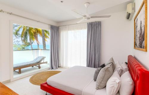 a bedroom with a bed and a red couch at Imani - Beachfront Penthouse with Spectacular Ocean Views in Kiwengwa