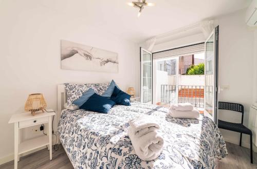 sypialnia z łóżkiem z niebieskimi poduszkami i oknem w obiekcie Babieca Casa con Garaje w mieście Zamora