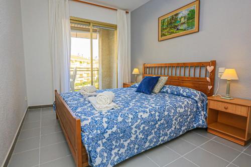 a bedroom with a bed with a blue comforter and a window at Golf D 201 ONLY FAMILIES in Cambrils