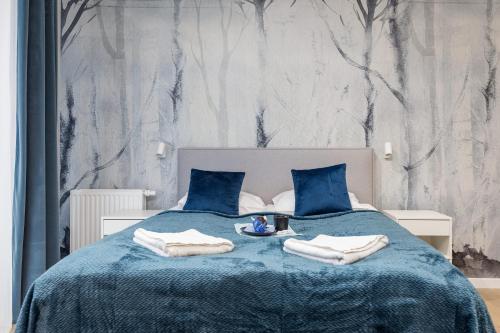 Un dormitorio con una cama azul con toallas. en Baltic Marina Residence Sauna & Fitness Apartments by Renters en Kołobrzeg