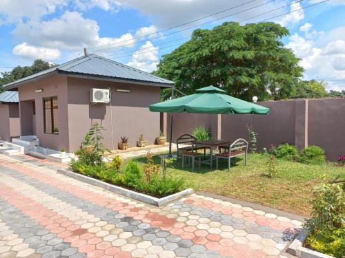 ein Haus mit einem Tisch und einem Sonnenschirm im Hof in der Unterkunft Kasuda three bedrooms house in Livingstone in Livingstone