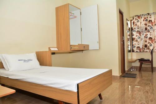 a bedroom with a bed with white sheets and a mirror at Hotel Sree Vasudev in Vijayawāda