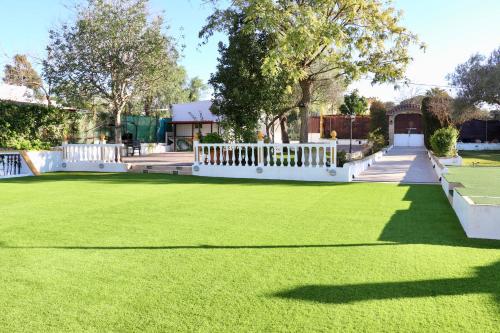 a lawn with a white fence and a tennis court at VILLA MACARENA in Espera