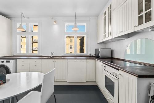 a white kitchen with white cabinets and a table at Rooms in quiet white villa apartment Hortensiavej 8 on Frederiksberg C in Copenhagen