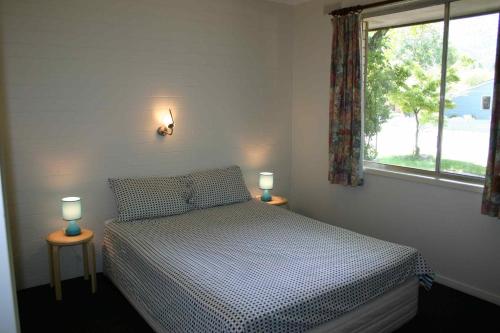 a bedroom with a bed and two lamps on tables at Ageri Holiday Unit in Bright