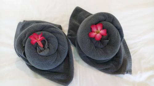 two black towels with red flowers on a bed at LANTA LUCKY HOUSE in Ko Lanta