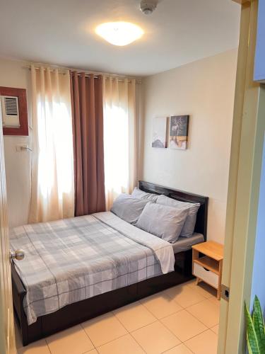 um quarto com uma cama num quarto com uma janela em One Spatial Two Bedroom Condominium Unit with Pool and Gym free Netflix and wifi em Iloilo
