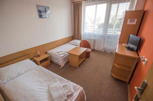 Habitación de hotel con cama, escritorio y TV. en Hotel Sport en Štětí
