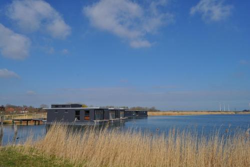 a house on a dock on a lake with tall grass at Hausboot der Friesländer im Wangermeer in Wangerland