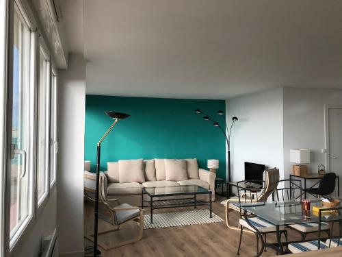 sala de estar con sofá y pared verde en L’Estacade, en Le Tréport