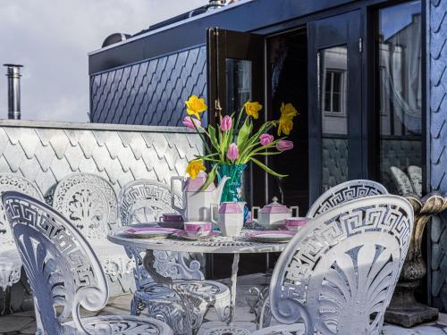 a table with chairs and a vase of flowers on a patio at Private and chique Salon de Franz - with large terrace in Amsterdam