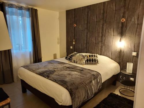 - une chambre avec un grand lit et un mur en bois dans l'établissement Au Vieux Séchoir, à Prudhomat