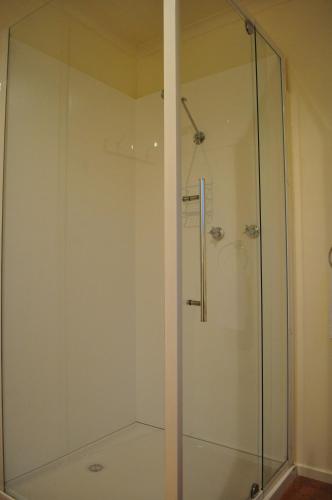 a shower with a glass door in a bathroom at GreenGate Cottages in Strahan