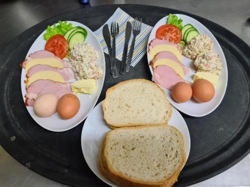 trois assiettes de nourriture sur un plateau noir avec des œufs et du pain dans l'établissement Agroturystyka U Siwego, à Rokitki
