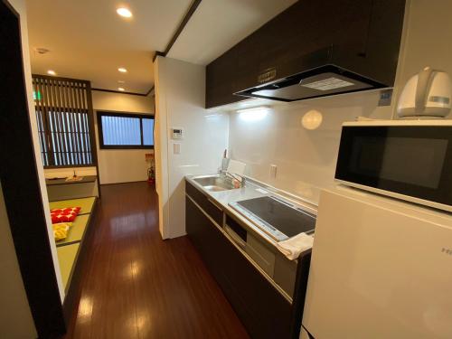 eine kleine Küche mit einer Spüle und einer Mikrowelle in der Unterkunft Yuzenkyo in Kyoto