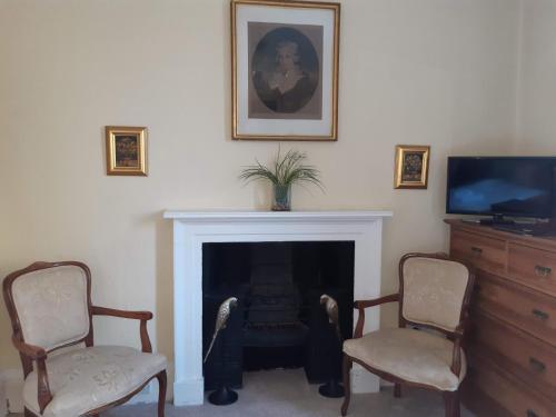 a living room with two chairs and a fireplace at Brocks in Bath