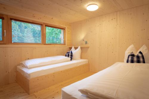 2 Betten in einem Zimmer mit Holzwänden und Fenstern in der Unterkunft Prefelnig Glamping Lodge Ossiacher See in Ossiach