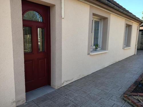 une porte rouge sur le côté d'une maison dans l'établissement Serge et annick, à Cérans-Foulletourte