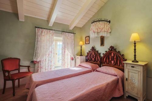 a bedroom with two beds and a chair and a window at Villa Melangola in Camaiore
