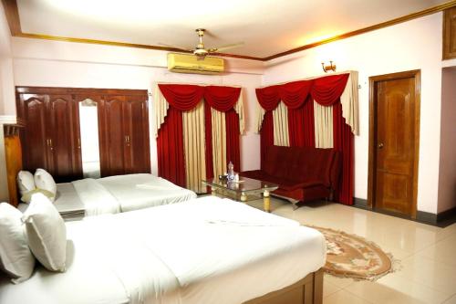 a bedroom with two beds and a couch in it at Hotel Heaven Inn in Dhaka