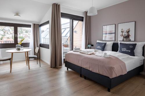 a bedroom with a large bed with a table and a window at Limehome Stuttgart Elsenhansstr in Stuttgart