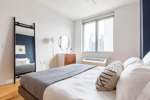 a white bedroom with a large bed and a mirror at Hells Kitchen 2BR w Pool DM nr Central Park NYC-469 in New York