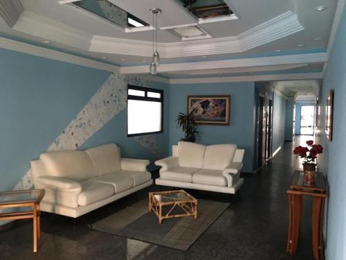 un soggiorno con 2 divani bianchi e un tavolo di María Cristina ,ar,Wi-Fi e tv a cabo a Praia Grande