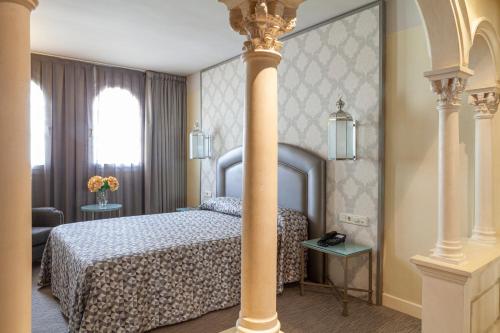 a hotel room with a bed and a column at Hotel Macià Alfaros in Córdoba