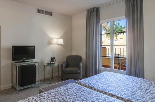 - une chambre avec un lit, une télévision et une fenêtre dans l'établissement Hotel Macià Alfaros, à Cordoue