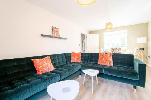 sala de estar con sofá verde y almohadas de color naranja en Brookfield, en Horley