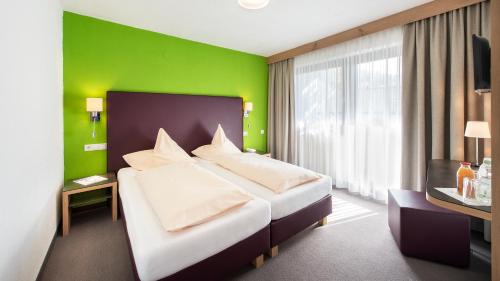 a bedroom with a large bed and a green wall at Hotel Erhart Sölden in Sölden