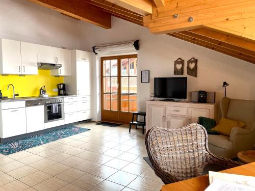 a kitchen with white cabinets and a tv in a room at Landhaus Obermaiselstein "THE VIEW" in Obermaiselstein