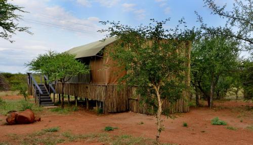 a wooden building with a staircase next to a tree at Tshukudu Game Lodge in Hoedspruit