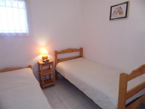 2 Betten in einem Zimmer mit einer Lampe auf einem Tisch in der Unterkunft Appartement Marseillan-Plage, 2 pièces, 4 personnes - FR-1-326-478 in Marseillan