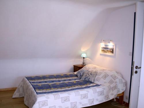 um pequeno quarto com uma cama e um candeeiro em Maison Locmaria, 5 pièces, 9 personnes - FR-1-418-12 em Locmaria