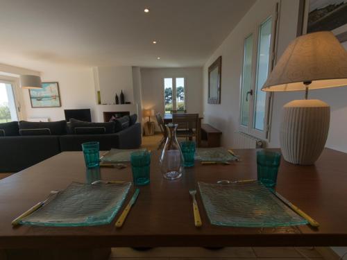 - une table à manger avec des assiettes et des verres verts dans l'établissement Maison récente avec jardin et wifi à Locmaria - FR-1-418-13, à Locmaria