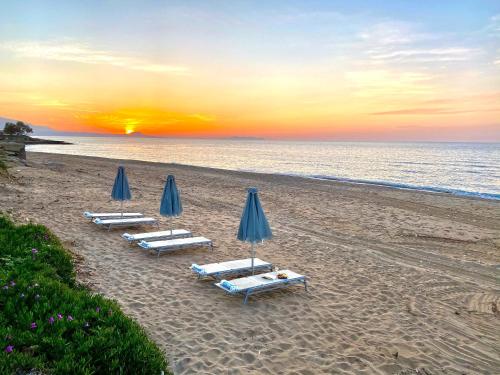 a group of lounge chairs and umbrellas on a beach at Golden Sand Beach Villa in Magnisía