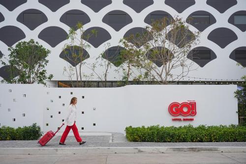 a woman walking down the street with her luggage at GO Hotel Bowin at Robinson Lifestyle Bowin in Si Racha