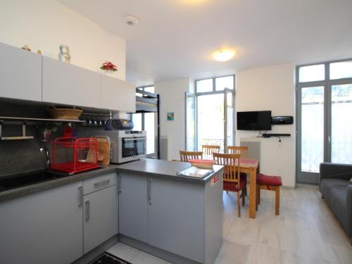 une cuisine avec des armoires blanches et un salon dans l'établissement Charmant T3 en centre-ville - 2 chambres - 42m² - Balconnets - Résidence avec ascenseur - 4 pers. - FR-1-608-164, à La Bourboule