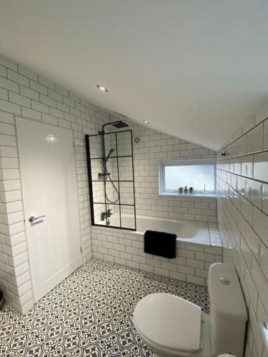 a white bathroom with a toilet and a window at Three bed, forest view home in Cwmcarn