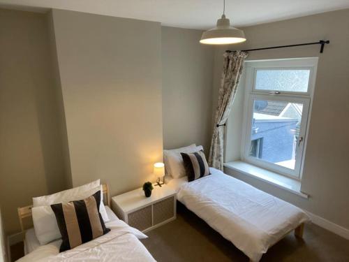 a bedroom with two beds and a window at Newly renovated, hi-spec three bed, forest view home in Cwmcarn