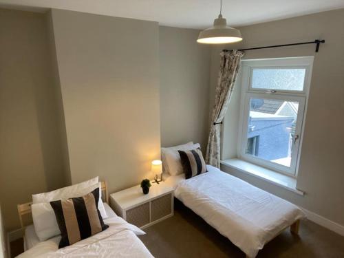 a bedroom with two beds and a window at Three bed, forest view home in Cwmcarn