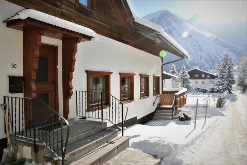 a house with snow on the porch and stairs at Alpin Haus Berwang in Berwang