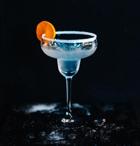 a blue drink in a glass with an orange slice at Hotel Stronie in Stronie Śląskie