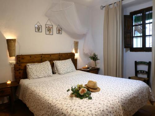 um quarto com uma cama com um chapéu e flores em Cortijo Rural La Gineta Alcalá la Real em Alcalá la Real