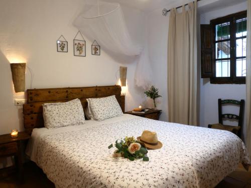 a bedroom with a bed with a hat and flowers on it at Cortijo La Gineta in Ermita Nueva