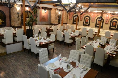 a restaurant with white tables and white chairs and tables and tablesearcher at Hotel Tomce Sofka in Skopje