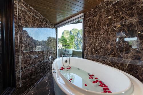 La salle de bains est pourvue d'une baignoire et d'une grande fenêtre. dans l'établissement Santa Maria Cruise Halong, à Hạ Long